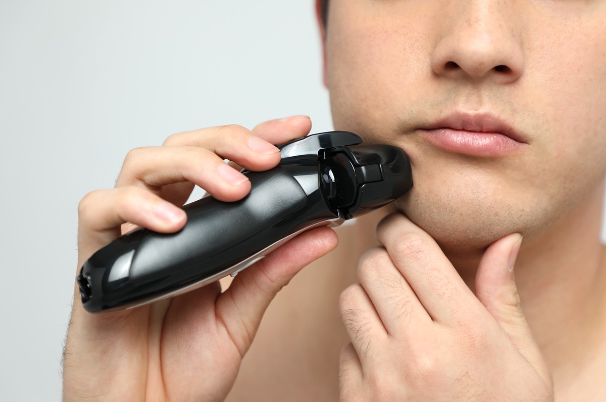 顎に手を当て髭を剃っている男性の画像