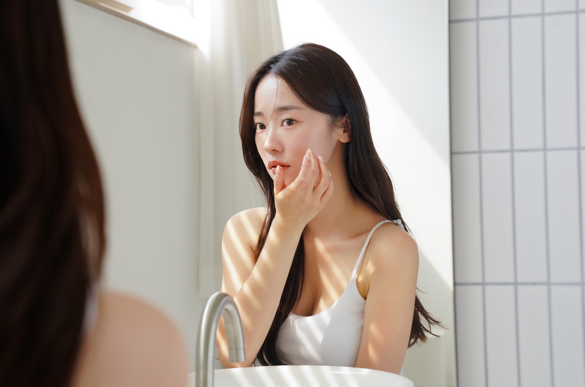 鏡で肌の状態をチェックする女性