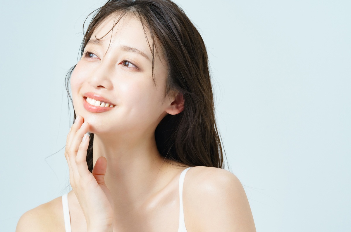 手を添えてほほ笑む女性の画像