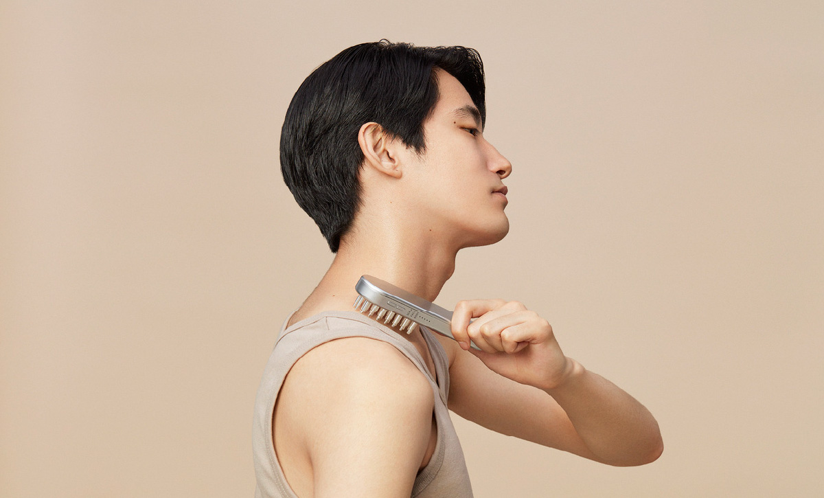 電気バリブラシを右肩に当てている男性