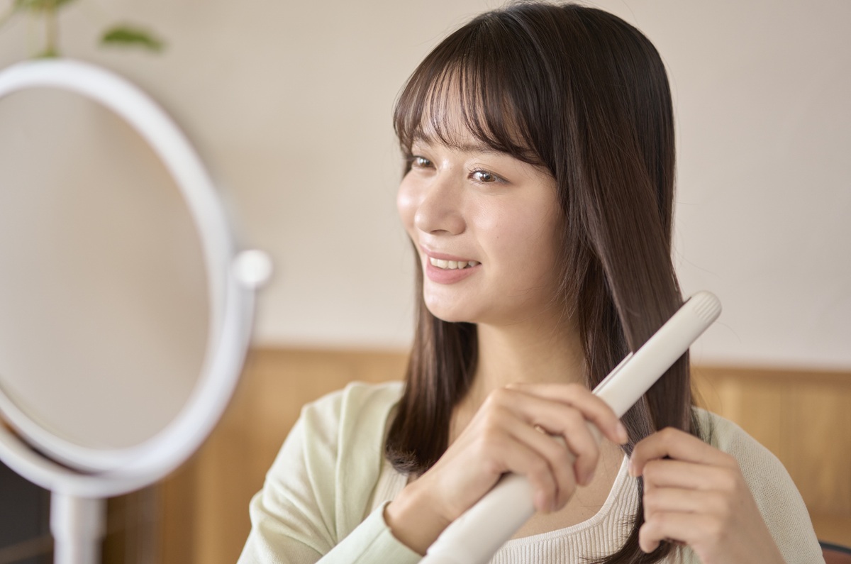 ヘアアイロンを使用して髪をスタイリングする女性の画像