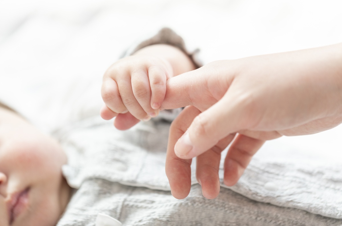 赤ちゃんが大人の指を握っているイメージ画像